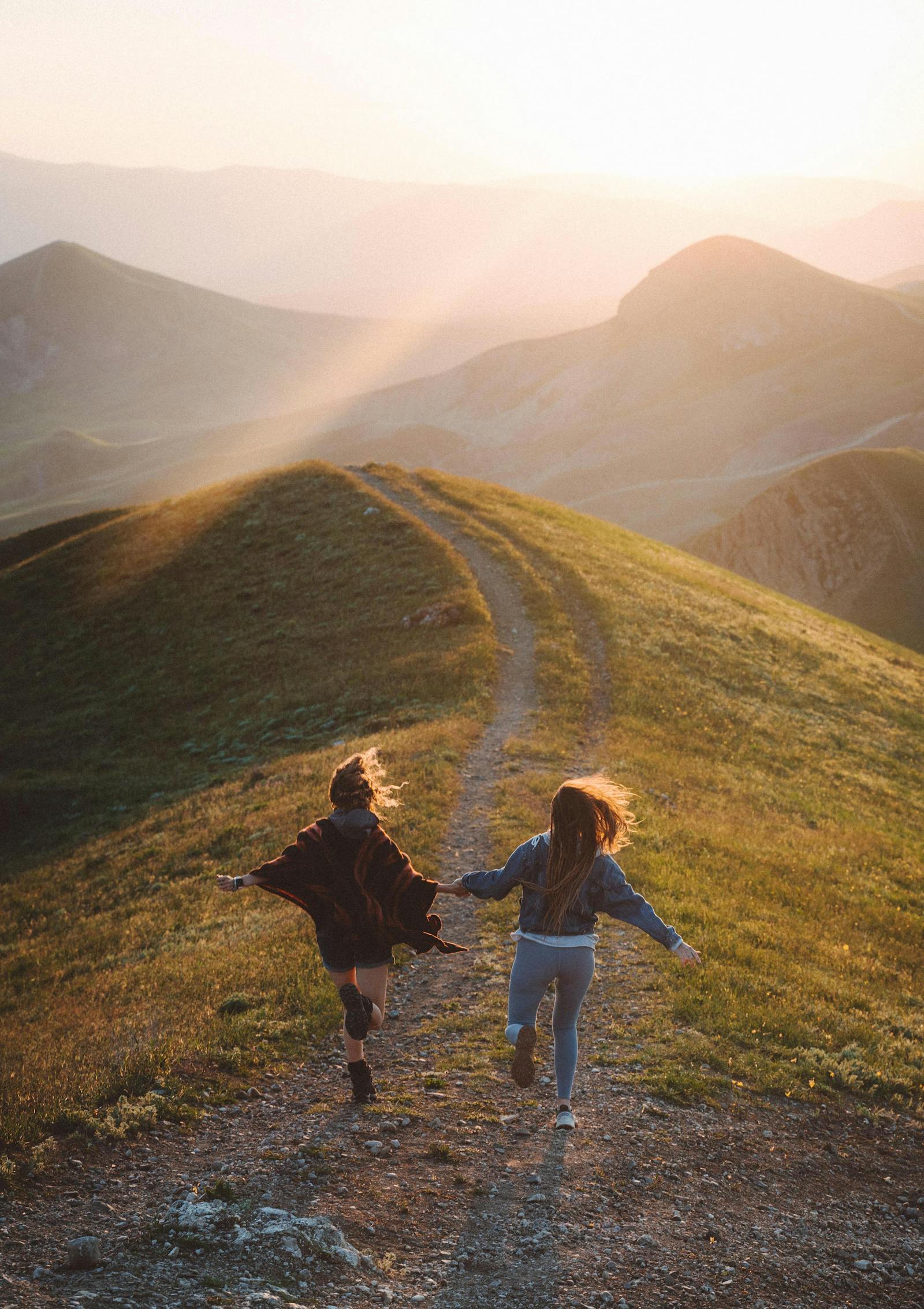 Two runners moving together on a trail in warm evening light